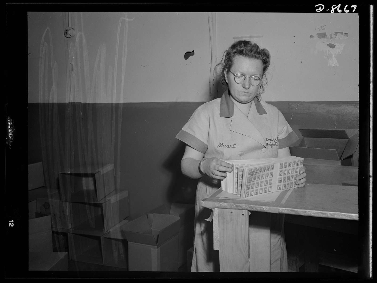 Printing war ration book 2. Ida Stuart quickly checks the assembled pages of ration books as they come from the cutter