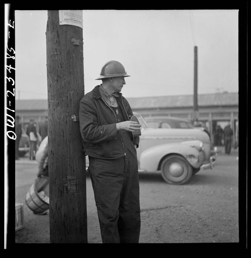 Bethlehem-Fairfield shipyards, Baltimore, Maryland. A shipyard worker looking at a time clock from outside of the yard