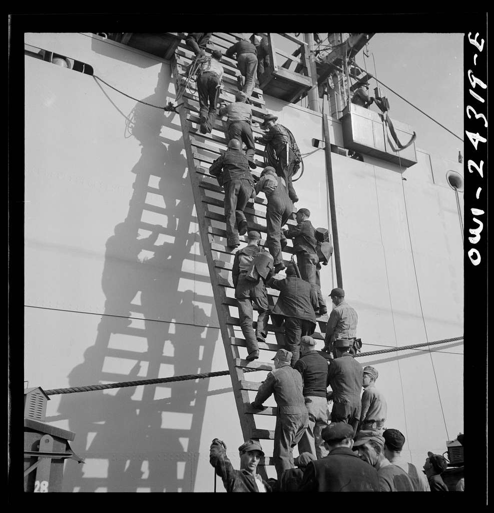 Bethlehem-Fairfield shipyards, Baltimore, Maryland. Workers on a ladder at the outfitting pier